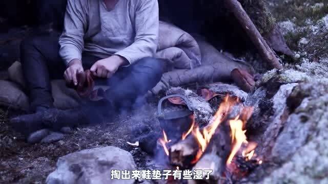 寒冷的冬天,流浪者在自建的荒野小屋,躲在纯皮被褥中喝热茶取暖 